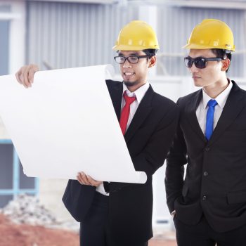 Architect and construction engineer or surveyor discussion plans and blueprints shot at construction site