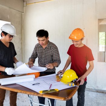 Engineer and architect discussing with foreman about project in building construction site