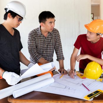 Engineer and architect discussing with foreman about project in building construction site