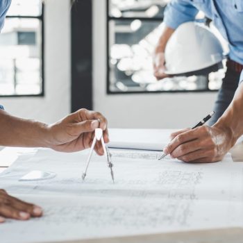 Hands of architect or engineer working on blueprint meeting for project working with partner on model building and engineering tools in working site, Construction concept.