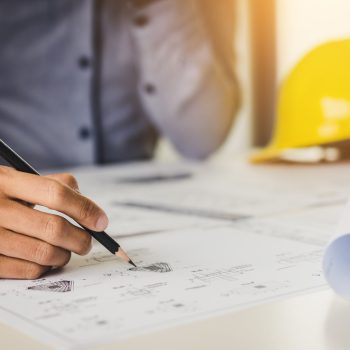Architect holding pencil and pointing on blueprint.
